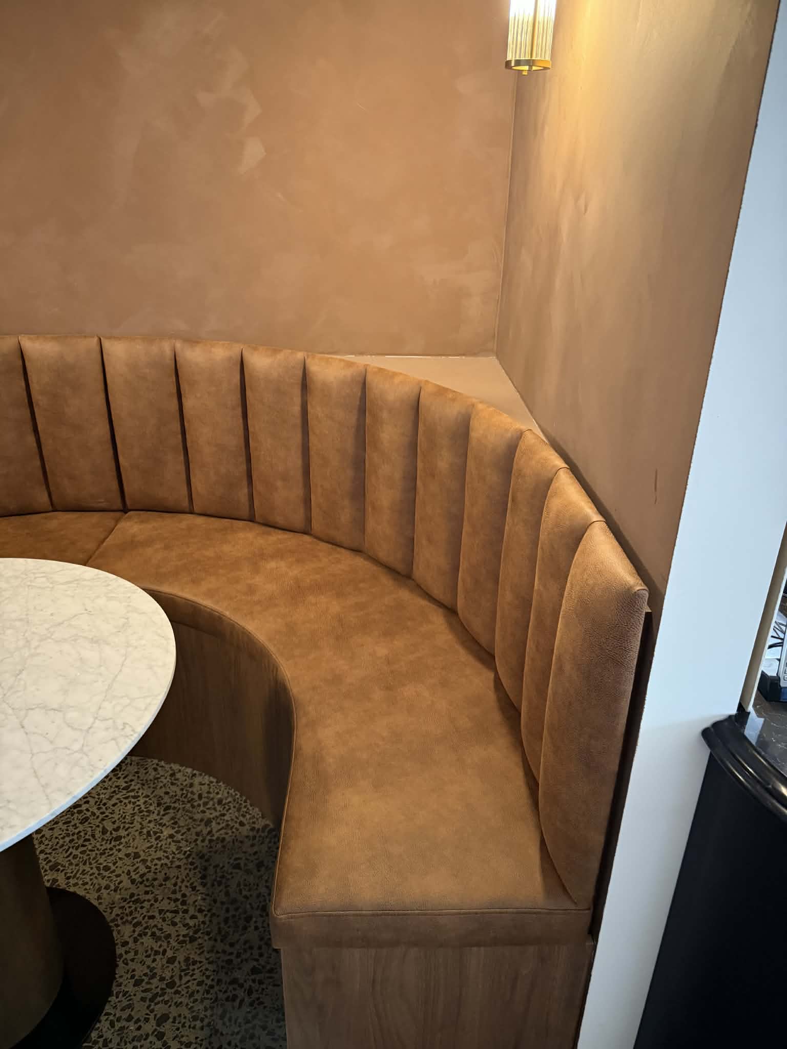 The banquette's fluted backrest curving into the corner of the room