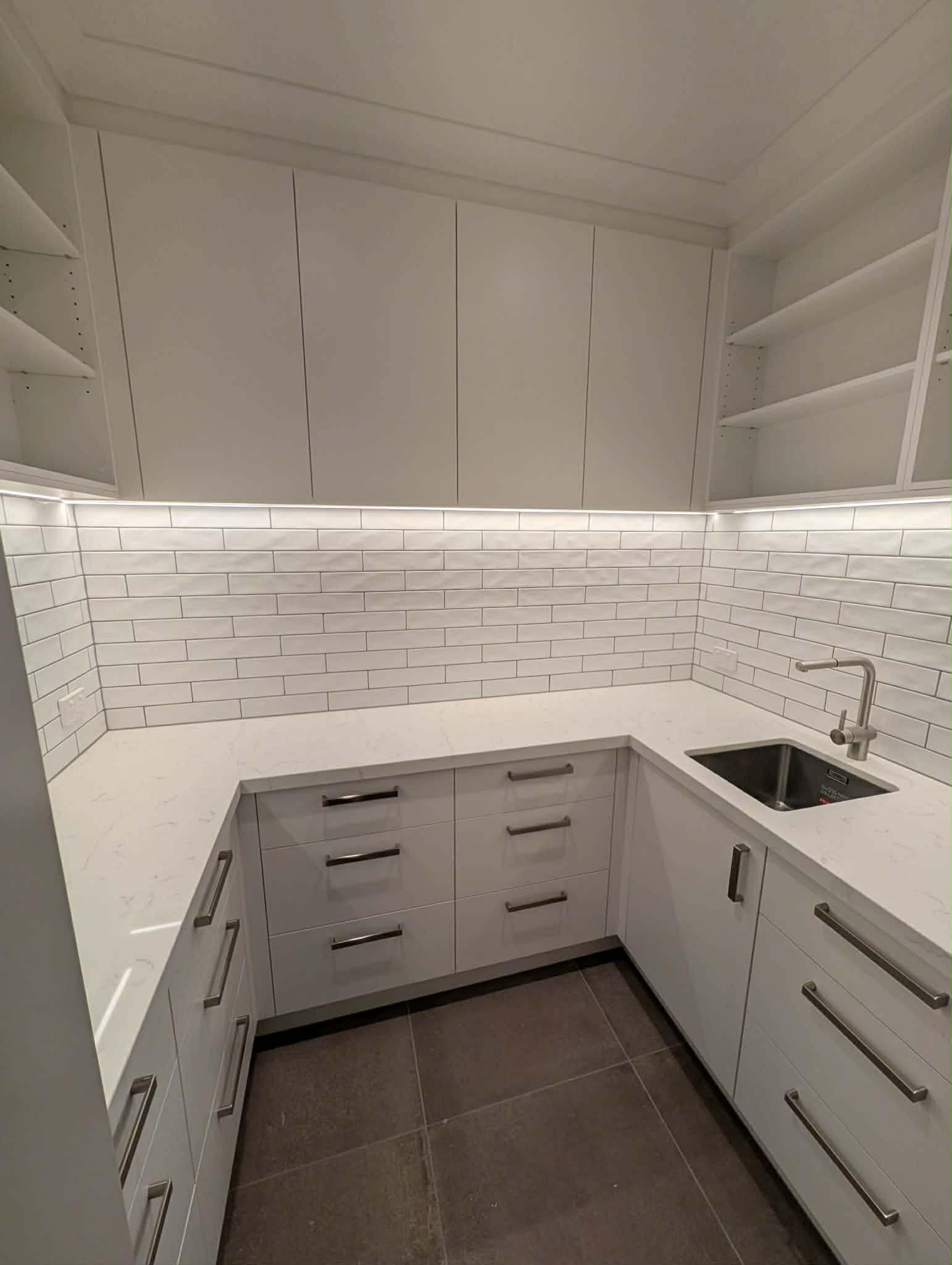 Butler's pantry with a stainless undermount sink, a bank of drawers and open shelving above