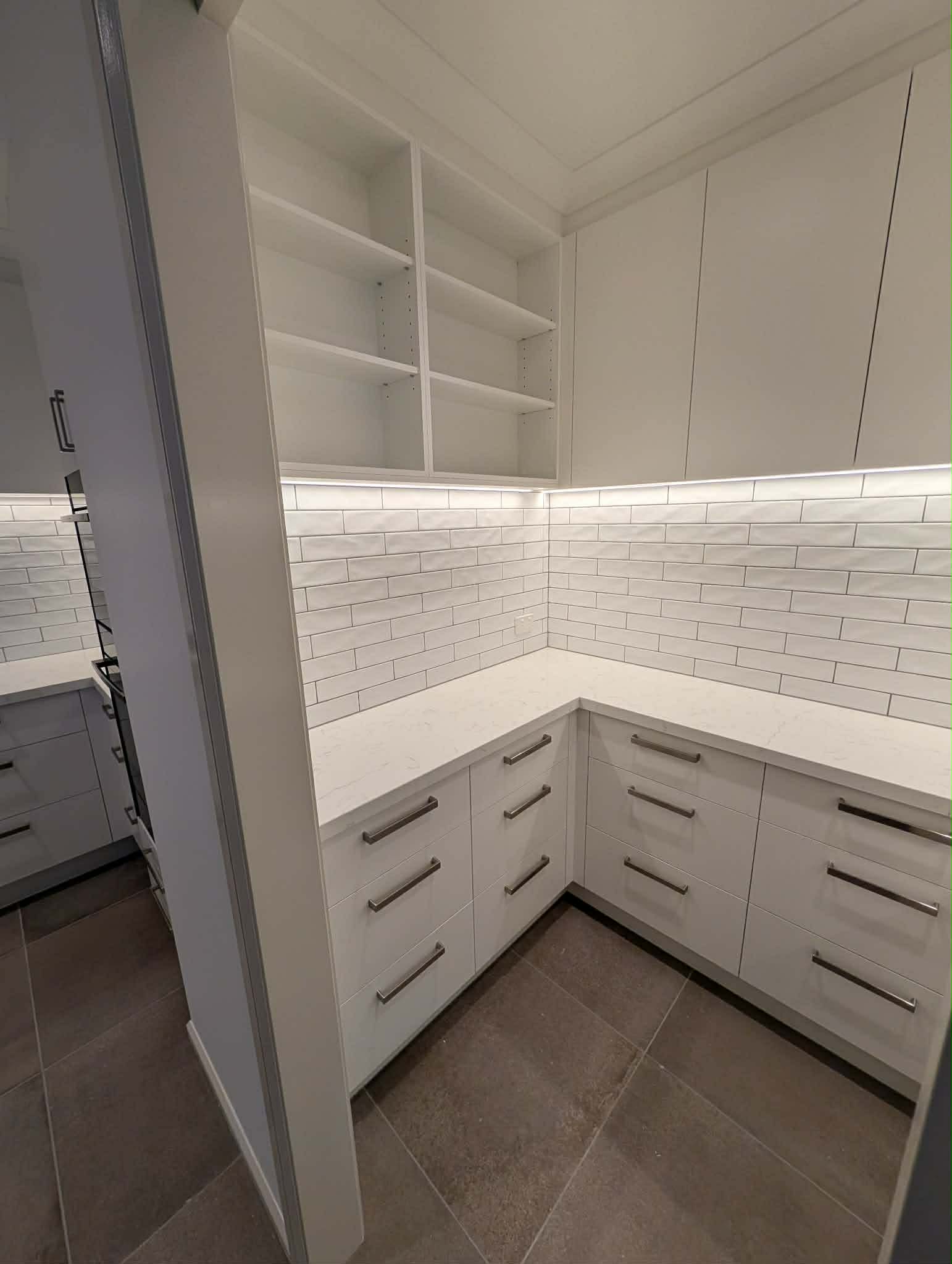 The butler's pantry seen from the doorway, with adjustable shelving and full-height cupboards