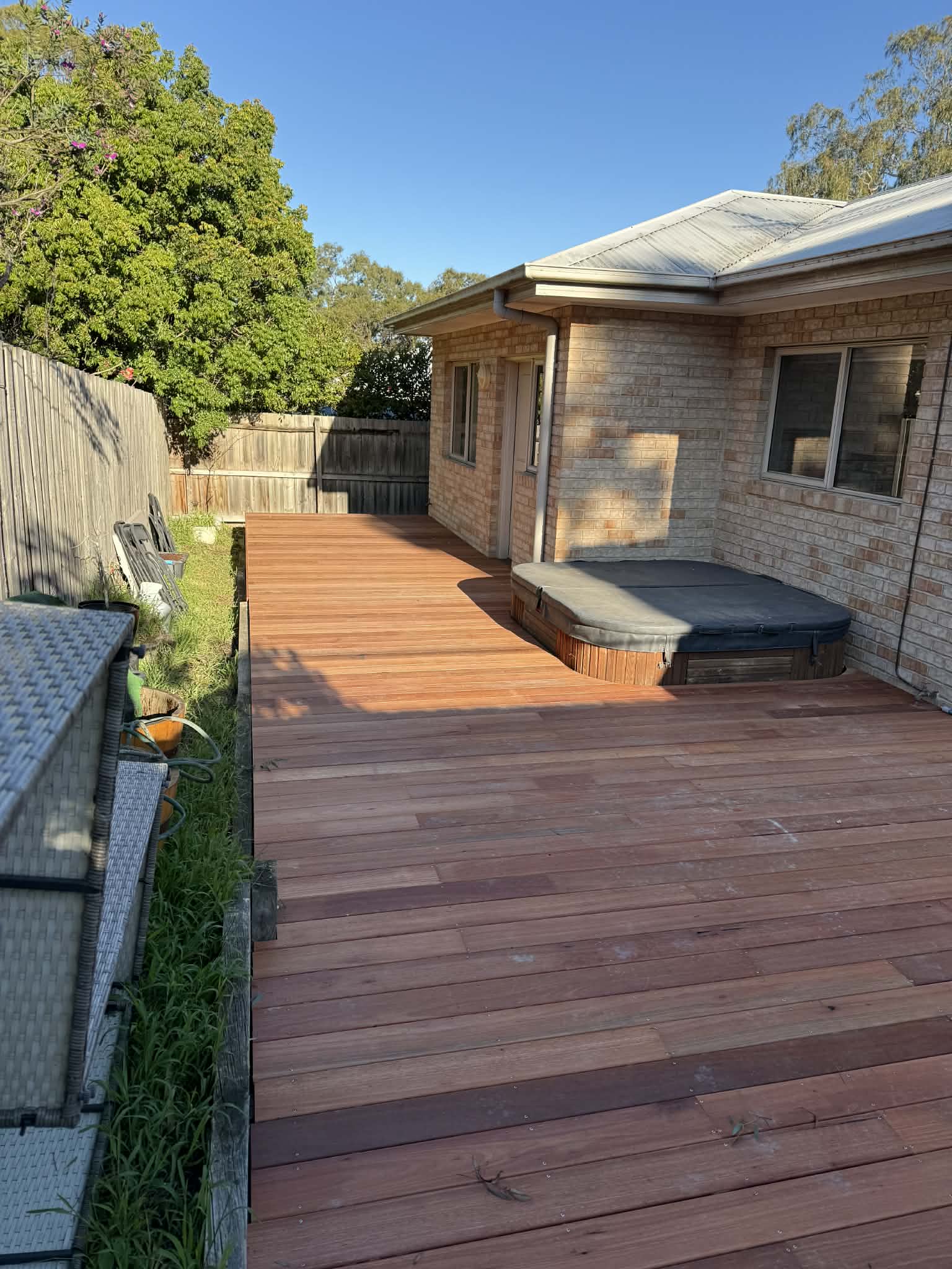 The deck continuing past a built-in spa, boards flush with the spa surround