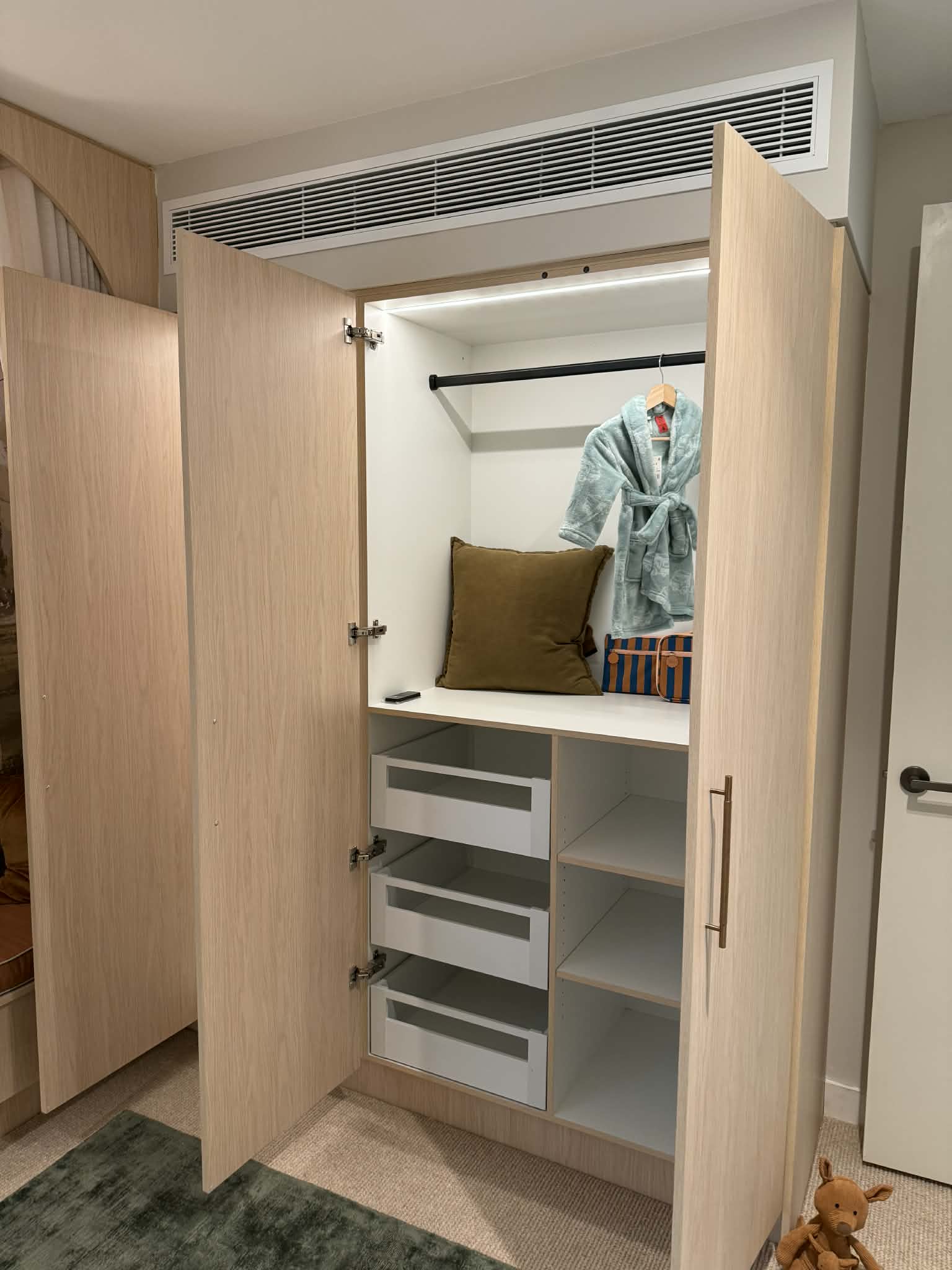 Inside the wardrobe from an angle, showing the drawers, the shelf above them and the light strip under the top