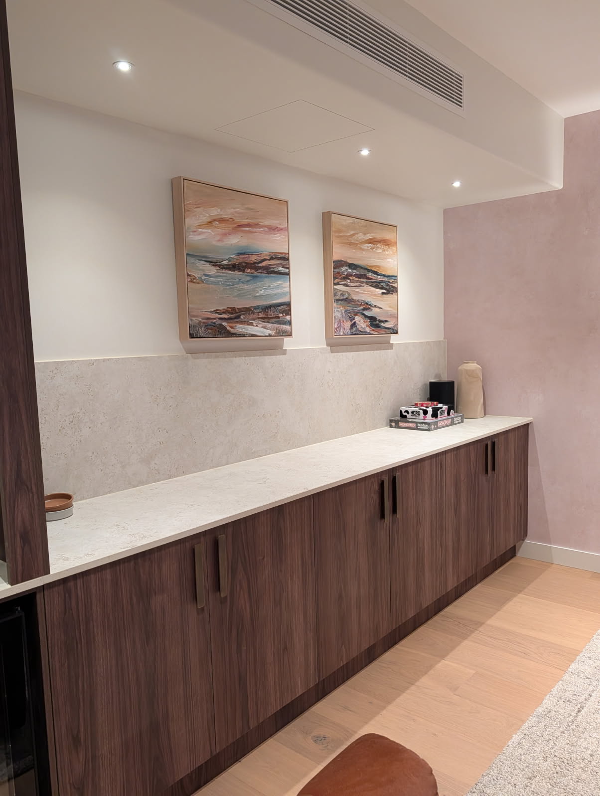 The run of two-door Rojo Walnut cupboards under a Dekton top, carrying on down the wall to the far corner