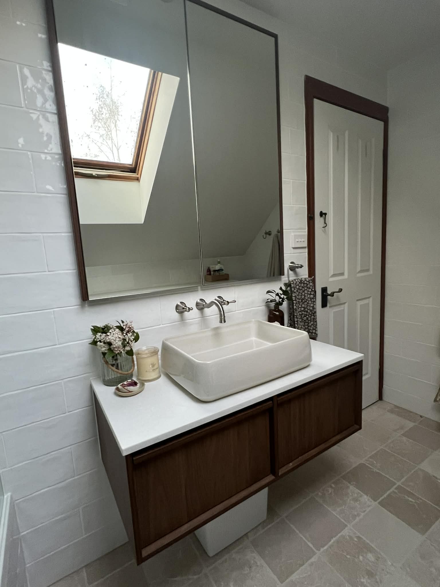 Wall-hung Florentine walnut vanity with a Firtina stone top and a Robert Gordon vessel basin, under a mirrored shaving cabinet