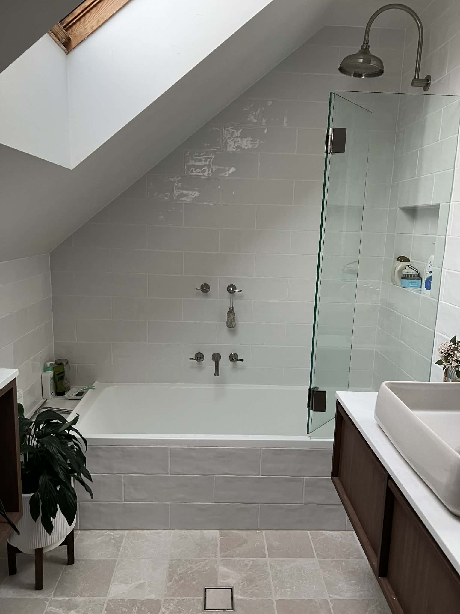 The bath set under the raked ceiling and skylight, with the walnut vanity at right