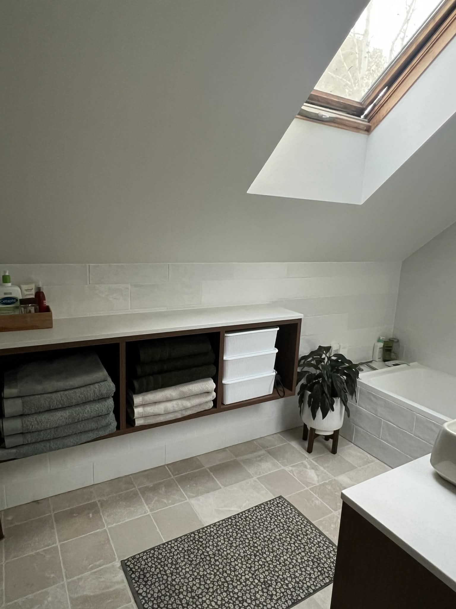 Wall-hung walnut towel cabinet with three open compartments and a stone top